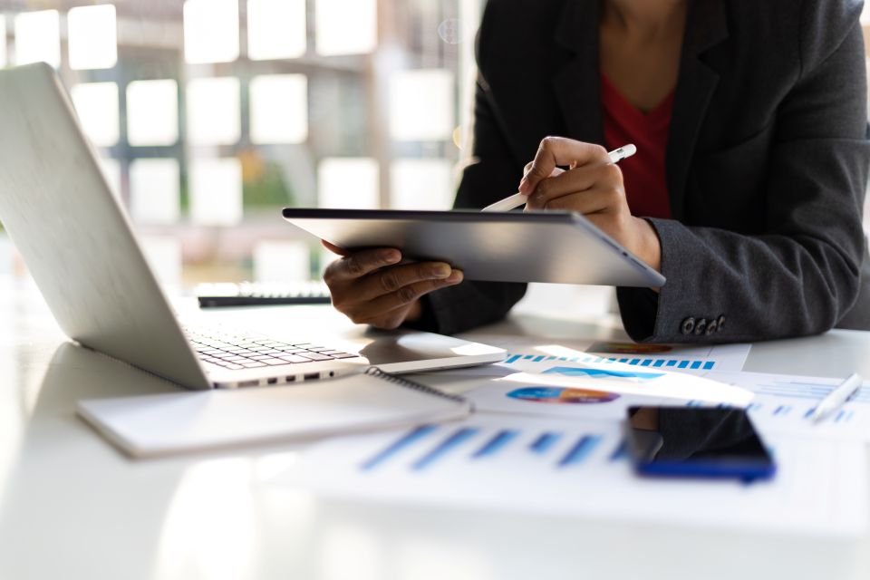 Assistante administrative gérant des tâches administratives sur tablette et ordinateur