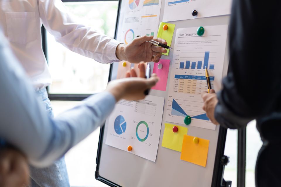 Professionnels analysant des graphiques et des indicateurs affichés sur un tableau de suivi.