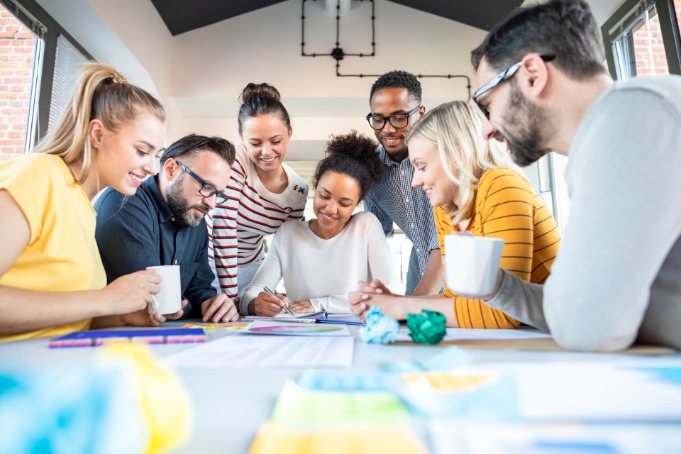 Groupe de professionnels travaillant ensemble autour d’une table dans une dynamique collaborative.
