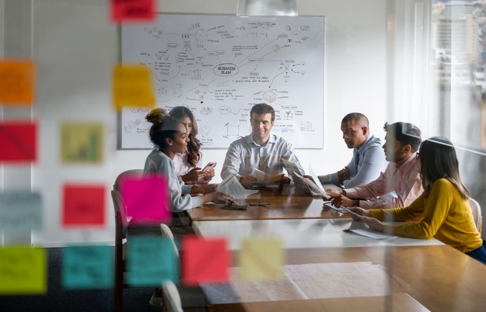 Groupe de professionnels réunis autour d’une table pour échanger sur un projet, avec des notes colorées au premier plan.